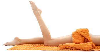 long legs of relaxed lady with orange towel over white